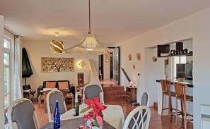 A spacious living area with a dining table, chairs, a sofa, and a kitchen area with a bar.