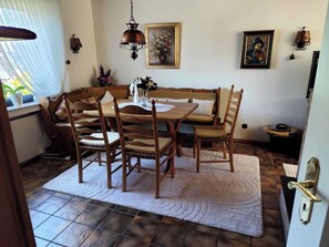 Un comedor con mesa y sillas de madera, un tapete estampado y cuadros colgados en la pared.