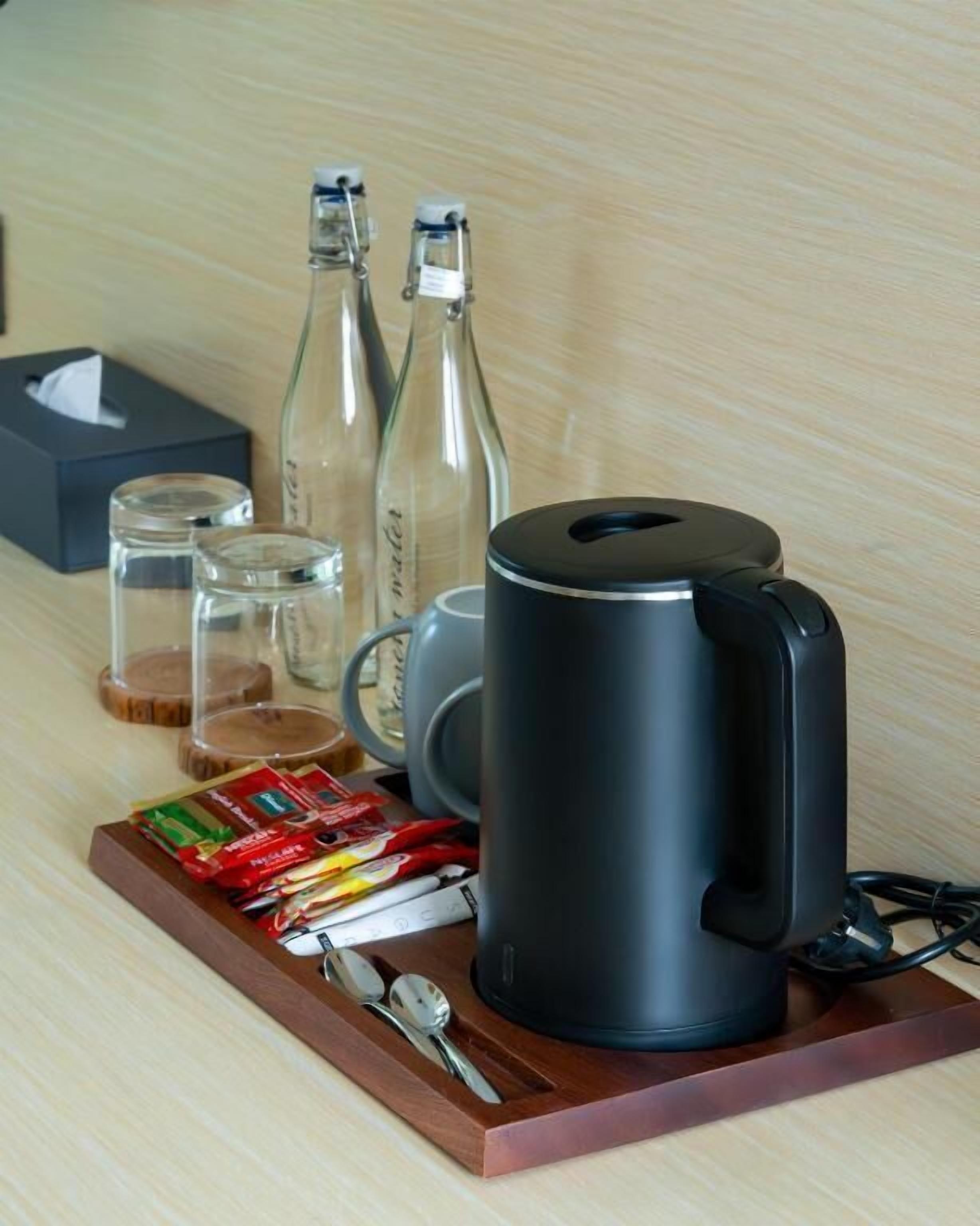 A coffee maker, two bottles, a tissue box, and a tray with snacks and utensils.