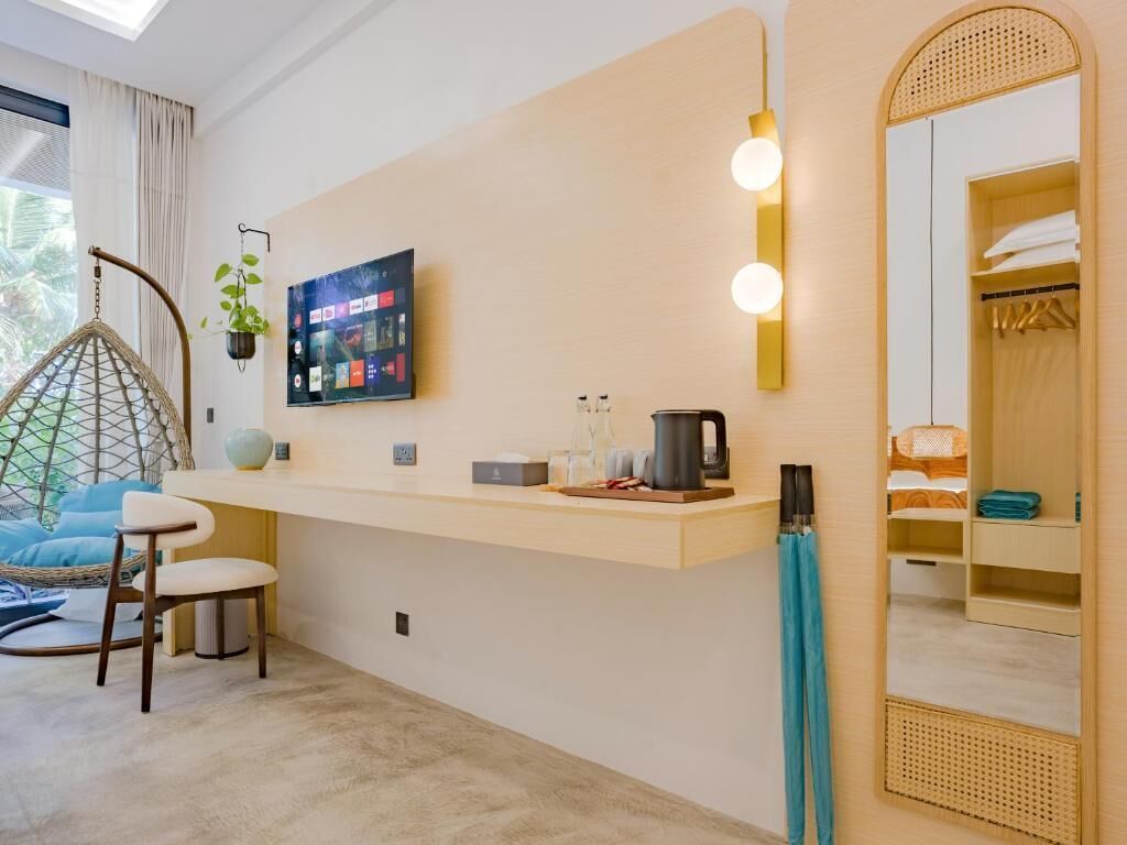 Une chambre moderne avec un fauteuil suspendu, une petite table, un téléviseur fixé au mur et un miroir.