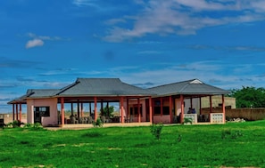 A two-story building with a covered patio area, a small garden, and a clear blue sky.