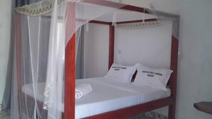 A single bed with a canopy, two pillows, and a white bedspread.