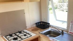 A compact kitchen with a gas stove, a sink, and wooden cabinets.