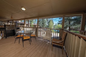 A covered outdoor area with a grill, dining table, and chairs, overlooking a natural landscape. - Innsbrook Vacation Condo 36 (Ruidoso)
