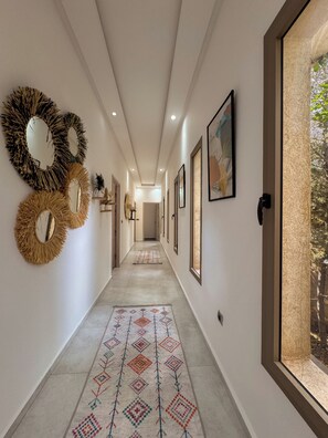 Un pasillo con espejos en la pared, obras de arte enmarcadas y una alfombra estampada.
