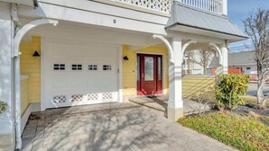 Ett tvåvåningshus med en inglasad veranda, en röd dörr och ett garage.