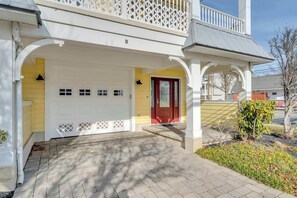 Ein zweistöckiges Haus mit überdachter Veranda, einer roten Tür und einer Garage.