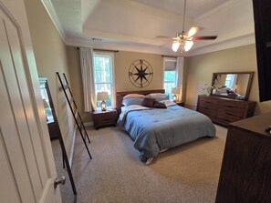 A bedroom with a bed, a nightstand, a dresser, a ceiling fan, a window with curtains, and a compass wall decoration. - Spacious 4-bedroom House in gorgeous Grovetown with AC (Grovetown)