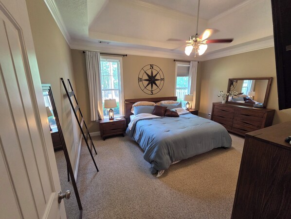 A bedroom with a bed, a nightstand, a dresser, a ceiling fan, a window with curtains, and a compass wall decoration. - Spacious 4-bedroom House in gorgeous Grovetown with AC (Grovetown)