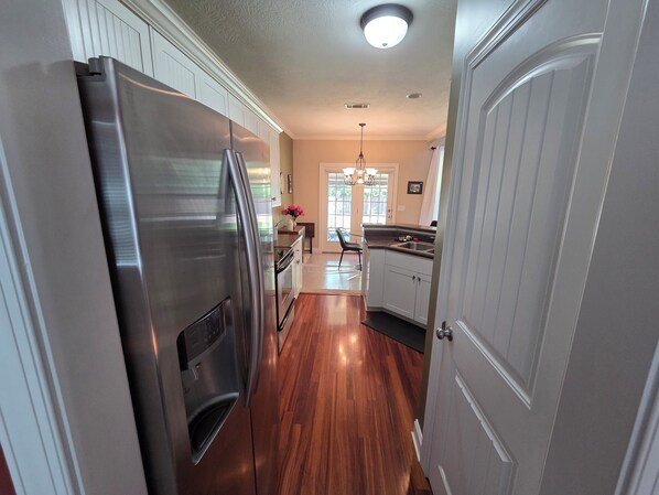 A kitchen with a stainless steel refrigerator, wooden flooring, and a door leading to another room. - Spacious 4-bedroom House in gorgeous Grovetown with AC (Grovetown)