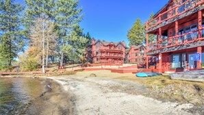 A red building with a balcony, a sandy beach, and trees. - Lake Front Resort Unit 31 (Tahoe Vista)