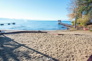 A beach with a pier extending into calm waters, a clear sky, and distant mountains. - Lake Front Resort Unit 31 (Tahoe Vista)