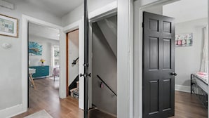 Un pasillo con piso de madera, una puerta blanca y una escalera que lleva a otra habitación.