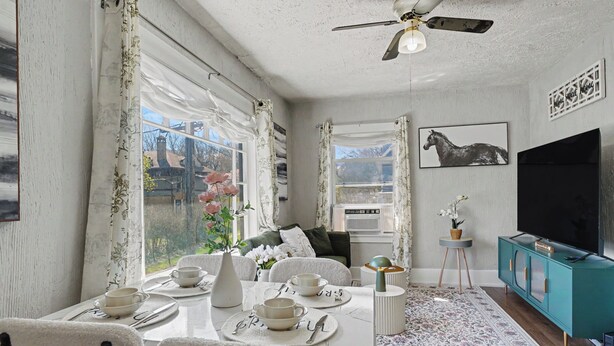 Un comedor con una mesa preparada para cuatro, un televisor y vistas al exterior.