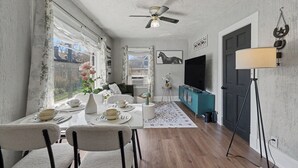 Un comedor con una mesa dispuesta para cuatro, un ventilador de techo y vistas al exterior.