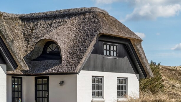 A house with a thatched roof, white walls, and a small porch with wicker furniture. - "Dorit" - 450m from the sea by Interhome (Blokhus)