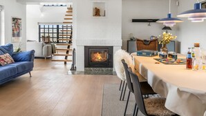 A modern living room with a fireplace, a dining area, and a staircase leading to an upper level. - "Dorit" - 450m from the sea by Interhome (Blokhus)