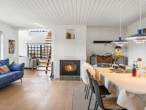 Una sala de estar moderna con chimenea, un comedor y una escalera que sube a un nivel superior.
