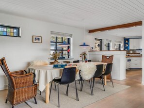 Ein Essbereich mit Korbstühlen, einem runden Tisch und einer weißen Tischdecke.
