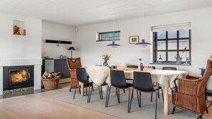 A modern living room with a fireplace, dining area, and large windows. - "Dorit" - 450m from the sea by Interhome (Blokhus)