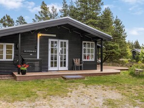 Eine Blockhütte mit Veranda, einem Schild mit der Aufschrift 'HE DEHUSE 63' und einem Blumentopf.