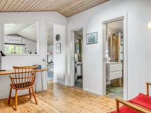 Ein modernes Interieur mit Holzboden, einem Essbereich mit einem Holzstuhl, einer Küche mit Spüle und einem Badezimmer mit Spiegel.