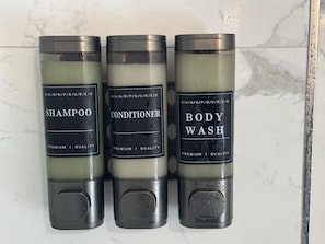 Three bottles of body wash, conditioner, and shampoo with labels indicating premium quality. - The EWR Transit Hub: Modern 3BR Near Newark & NYC (Irvington)
