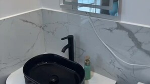 Une salle de bain avec un lavabo noir, un miroir et des toilettes blanches.