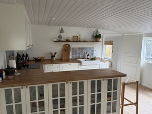 A kitchen with a wooden countertop, white cabinets, and a window with a view. - "Benja" -  from the sea by Interhome (Hals)