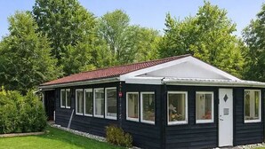 Ein eingeschossiges, schwarzes Gebäude mit rotem Dach, großen Fenstern und einer kleinen Veranda.