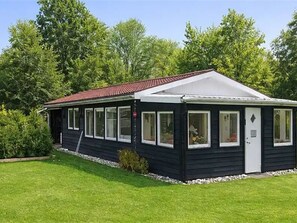 A single-story, black building with a red roof, large windows, and a small porch area. - "Benja" -  from the sea by Interhome (Hals)