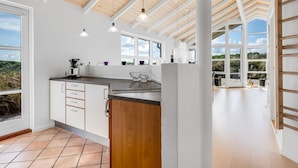 Uma cozinha moderna com uma ilha grande, armários brancos e vista para o exterior.