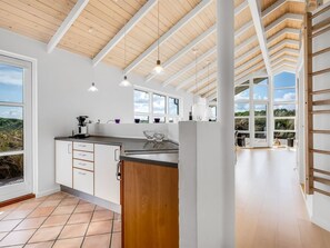 Cocina moderna con una isla grande, armarios blancos y vistas al exterior.
