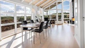 Uma sala de jantar espaçosa com pé direito alto e grandes janelas que oferecem vista para a paisagem.