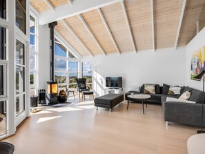 Un salón amplio con un ventanal grande, una chimenea, un sofá, un televisor y un cuadro en la pared.