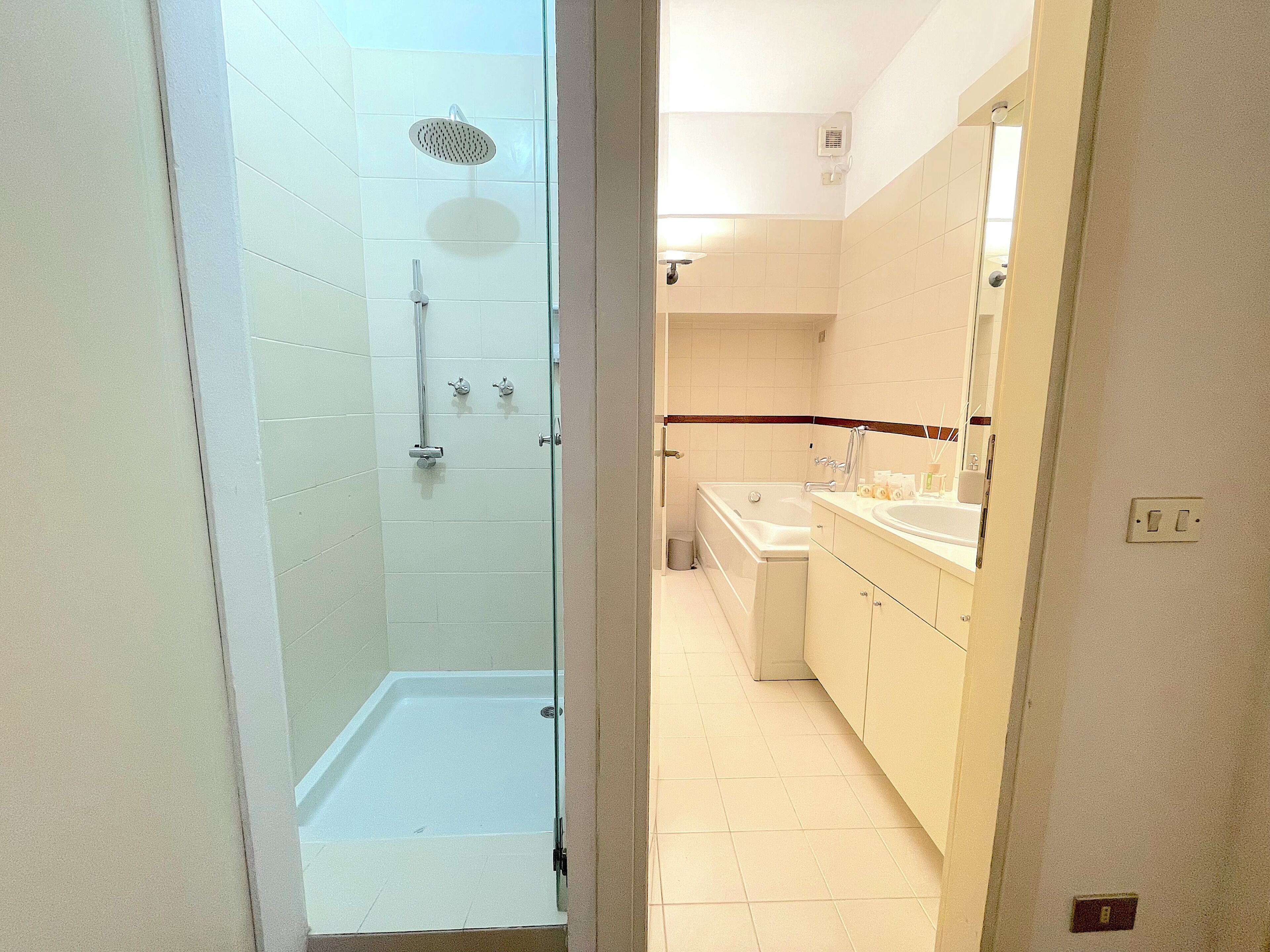 A bathroom with a glass-enclosed shower, a bathtub, and a vanity with a mirror.