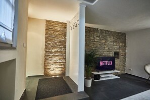 A modern living room with a stone accent wall, a Netflix TV, and a minimalist design.