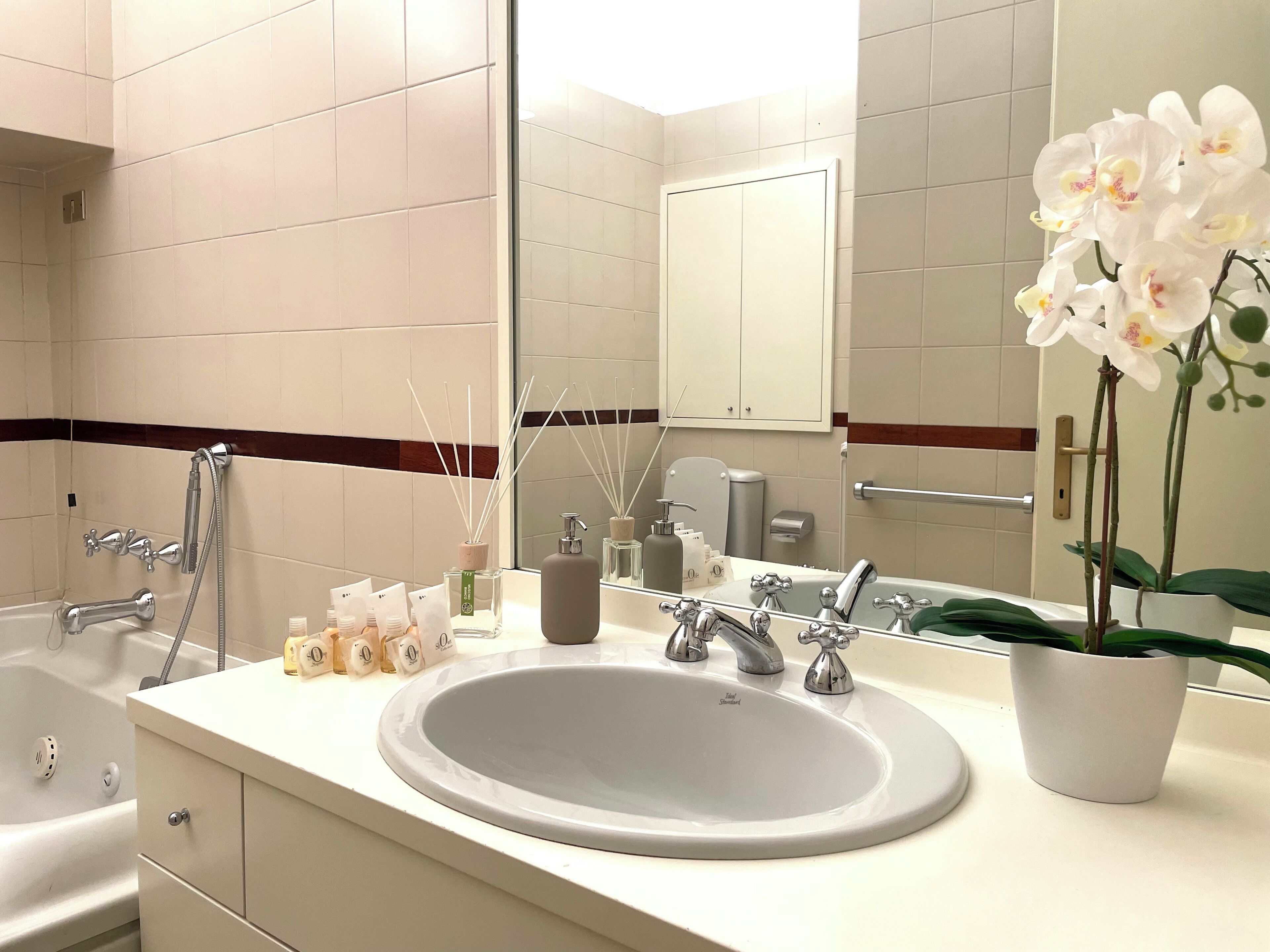 Un bagno moderno con un lavandino spazioso, due rubinetti, una doccia e uno specchio.
