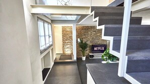 A modern interior with a staircase, a stone wall, and a Netflix sign. - Atlas Apartments - Città Alta (Bergamo)