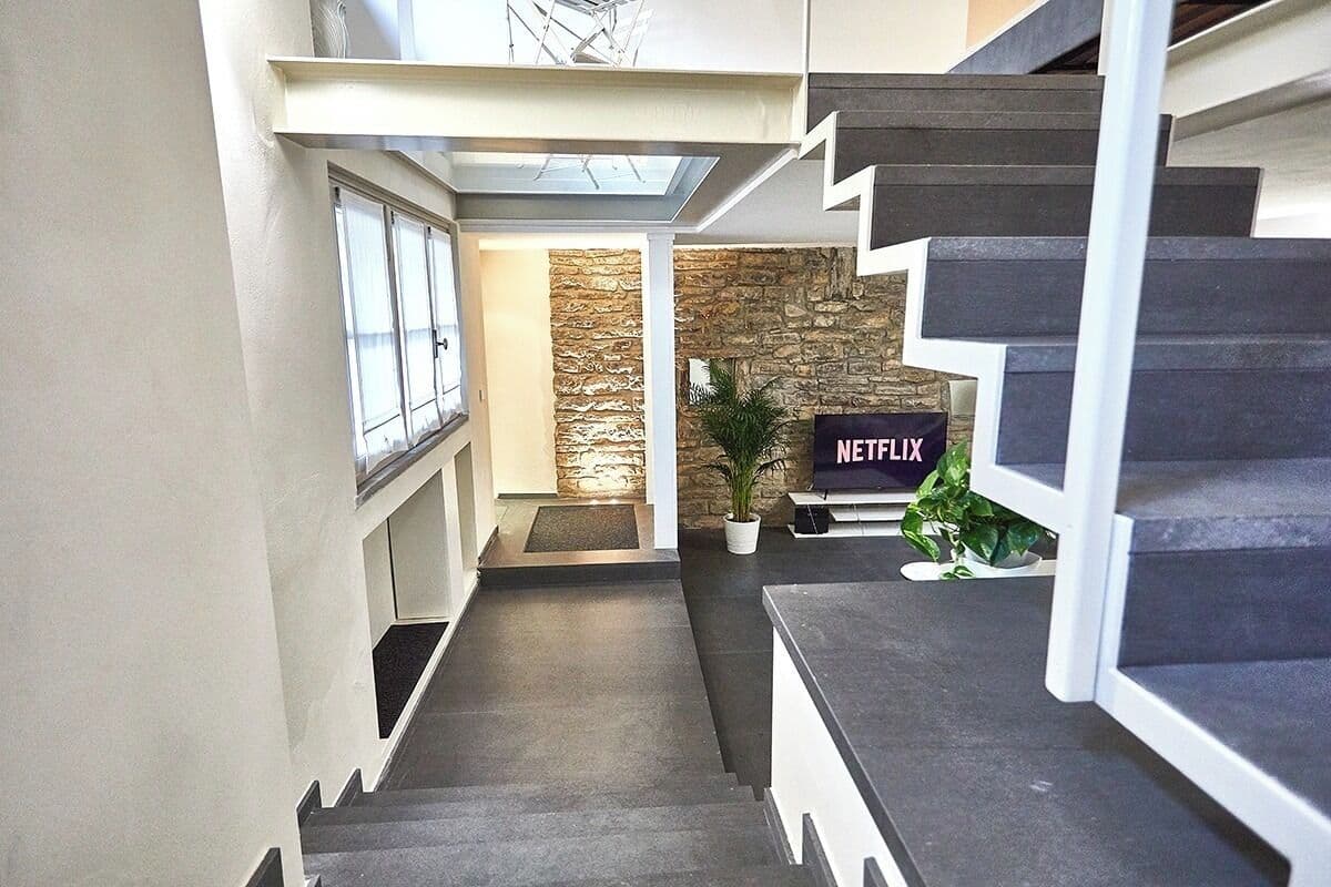 A modern interior with a staircase, a stone wall, and a Netflix sign.