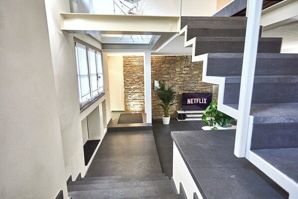 A staircase leading to a living area with a stone wall and a Netflix sign.