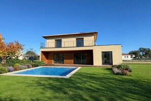 A modern two-story house with a swimming pool, a well-maintained lawn, and a clear blue sky. - New villa with pool (Ghisonaccia)