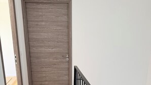 Eine Holztür, eine Treppe mit schwarzen Geländern und ein Holzboden.