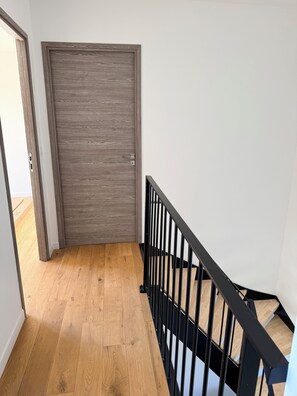 A wooden door, a staircase with black railings, and a wooden floor. - New villa with pool (Ghisonaccia)