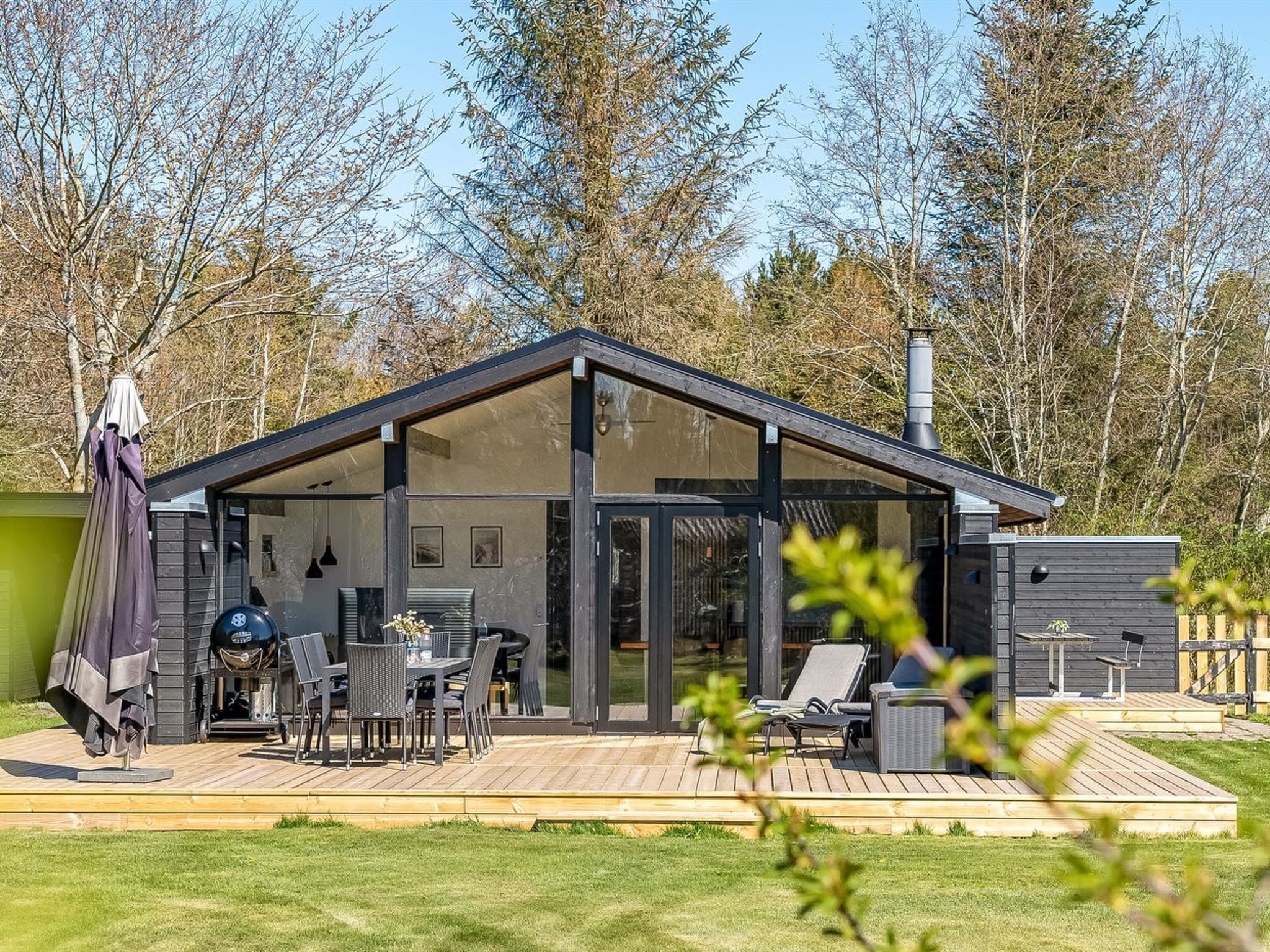 Une maison moderne dotée d’une terrasse, d’un espace salon extérieur et d’une cheminée.