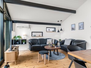 A modern living room with a sofa, a round table, and a wooden floor. - "Gojko" -  from the sea by Interhome (Hals)