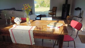 Un coin repas avec une table en bois, un banc, un vase de fleurs et un livre.