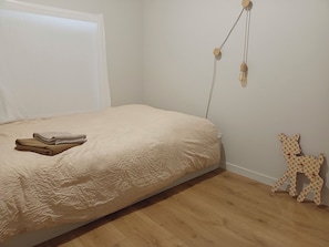 Une chambre à coucher comprenant un lit, un luminaire fixé au mur et une petite figurine d’animal décorative.