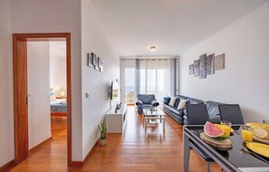 Ein modernes Wohnzimmer mit Sofa, Couchtisch und Essbereich mit Frühstücksangeboten.