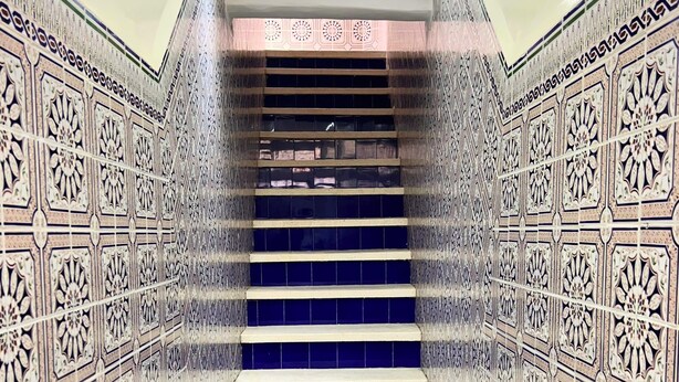 A staircase with intricate tile patterns on the walls and a blue-tiled floor.